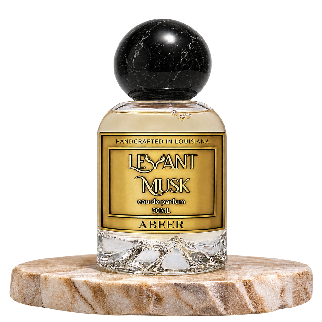 A bottle of Levant Musk Eau de Parfum labeled Abeer, featuring a clear glass bottle with a black marble sphere cap, set on a round marble pedestal against a white background.