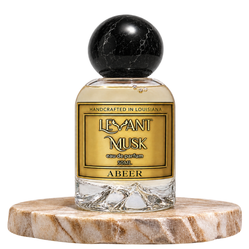 A bottle of Levant Musk Eau de Parfum labeled Abeer, featuring a clear glass bottle with a black marble sphere cap, set on a round marble pedestal against a white background.