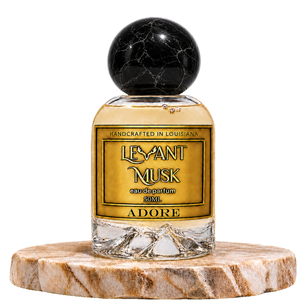 A bottle of Levant Musk Eau de Parfum named ADORE, featuring a gold label and a black marble spherical cap, displayed on a round marble pedestal against a white background.