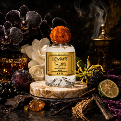 A bottle of Aisha by Levant Musk eau de parfum with a round amber cap, displayed on a marble coaster surrounded by dark purple orchids, a lime, dark plums, vanilla beans, and a smoking incense burner in a dark, moody setting.