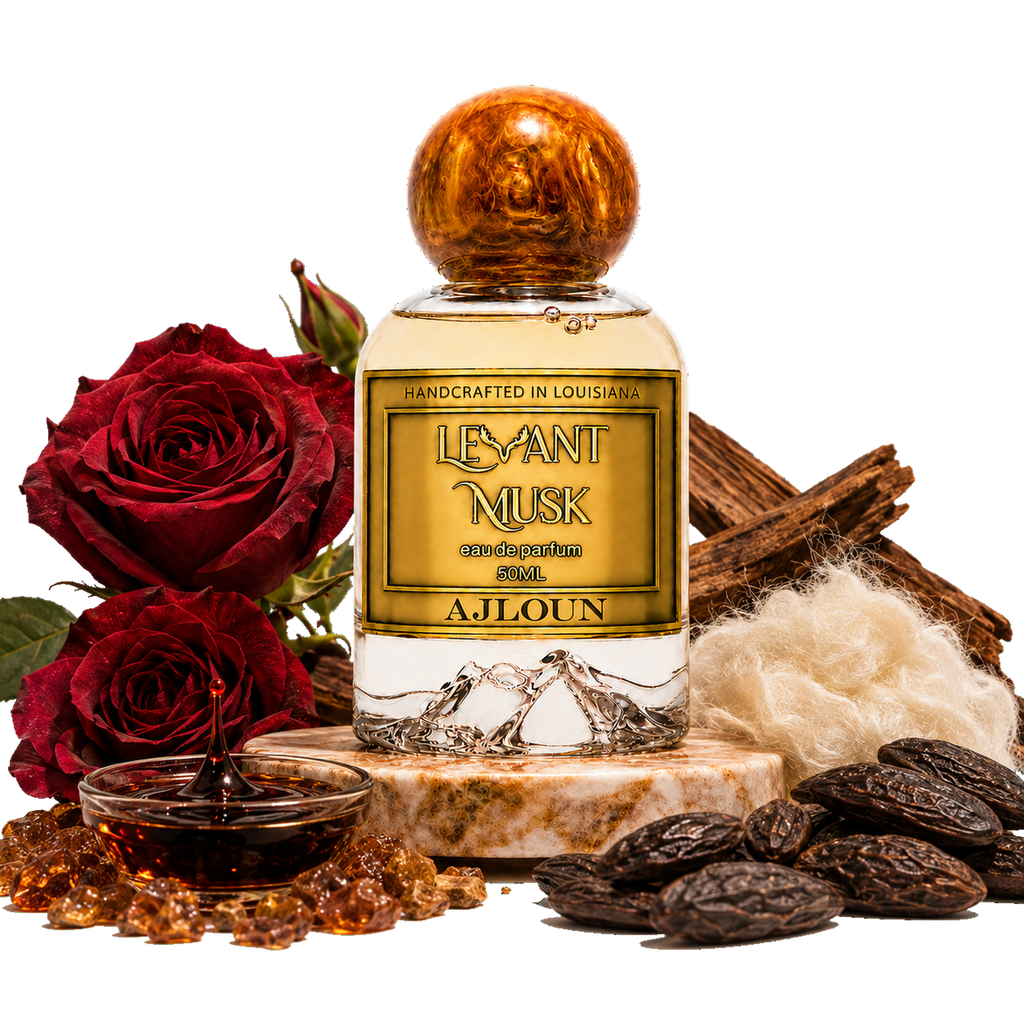 A bottle of AJLOUN eau de parfum by Levant Musk centered on a white background, surrounded by decorative ingredients including red roses, amber honey, dates, wood bark, and white wool. The bottle has a gold label and a metallic gold cap.