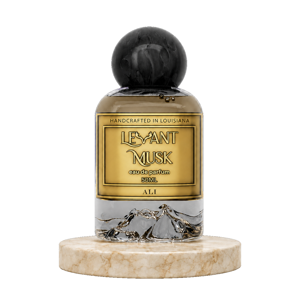 A 50ml bottle of 'Levant Musk' eau de parfum  named 'ALI', featuring a gold label with black lettering, a black marble-textured cap, and a silver mountain graphic near the base. The bottle is displayed on a round beige marble pedestal against a solid white background.