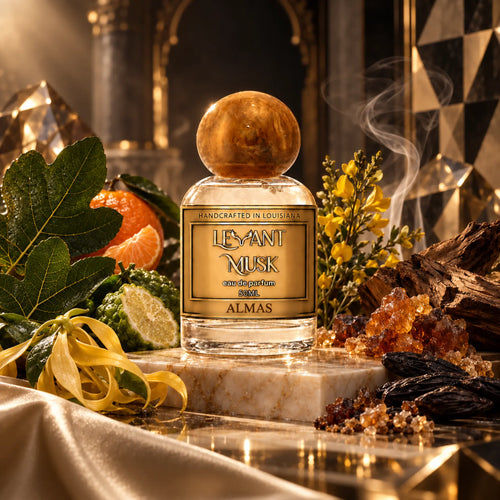 A perfume bottle labeled 'Levant Musk' eau de parfum named 'Almas' sits on a marble slab in a richly styled setting with citrus fruits, green leaves, yellow flowers, crystals, and dark wood, under warm dramatic lighting.