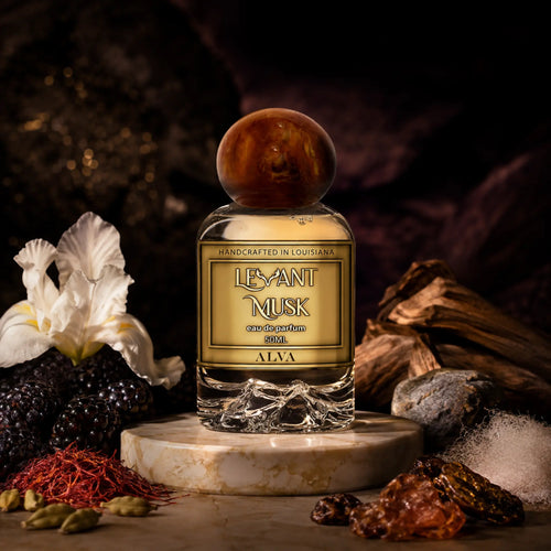A bottle of ALVA by Levant Musk Eau de Parfum centered on a marble pedestal, surrounded by dark berries, a white flower, spices, and wood against a dark atmospheric background.