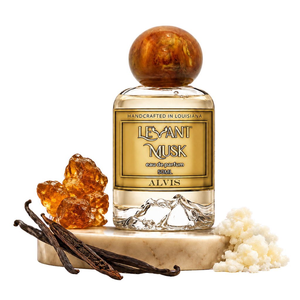 A bottle of Alvis Levant Musk Eau de Parfum with a gold label and a round amber-toned cap, displayed on a marble pedestal with vanilla beans and pale clustered pieces against a transparent background.