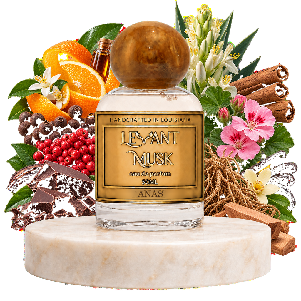A perfume bottle labeled 'LEVANT MUSK' eau de parfum named 'ANAS' stands centered on a white marble pedestal, surrounded by decorative ingredients and botanicals including oranges, cinnamon sticks, flowers, berries, chocolate, and wood pieces on a black background.
