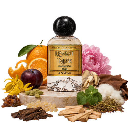 A bottle of Anwar by Levant Musk Eau de Parfum centered on a marble pedestal, surrounded by its natural ingredients including oranges, a plum, cardamom, cotton, musk, and flowers.