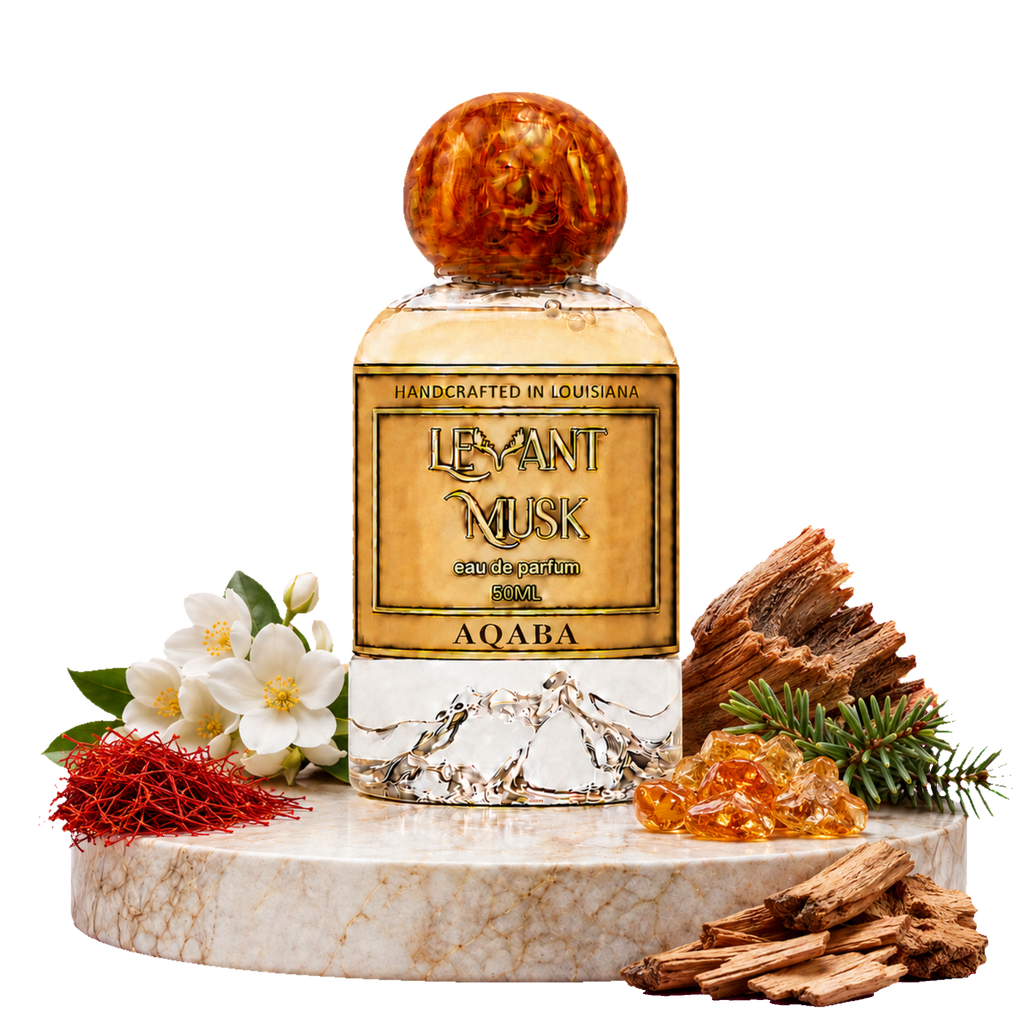 A bottle of Aqaba Levant Musk eau de parfum centered on a white marble pedestal, surrounded by white flowers, red saffron threads, amber resin, and wood pieces on a black background.