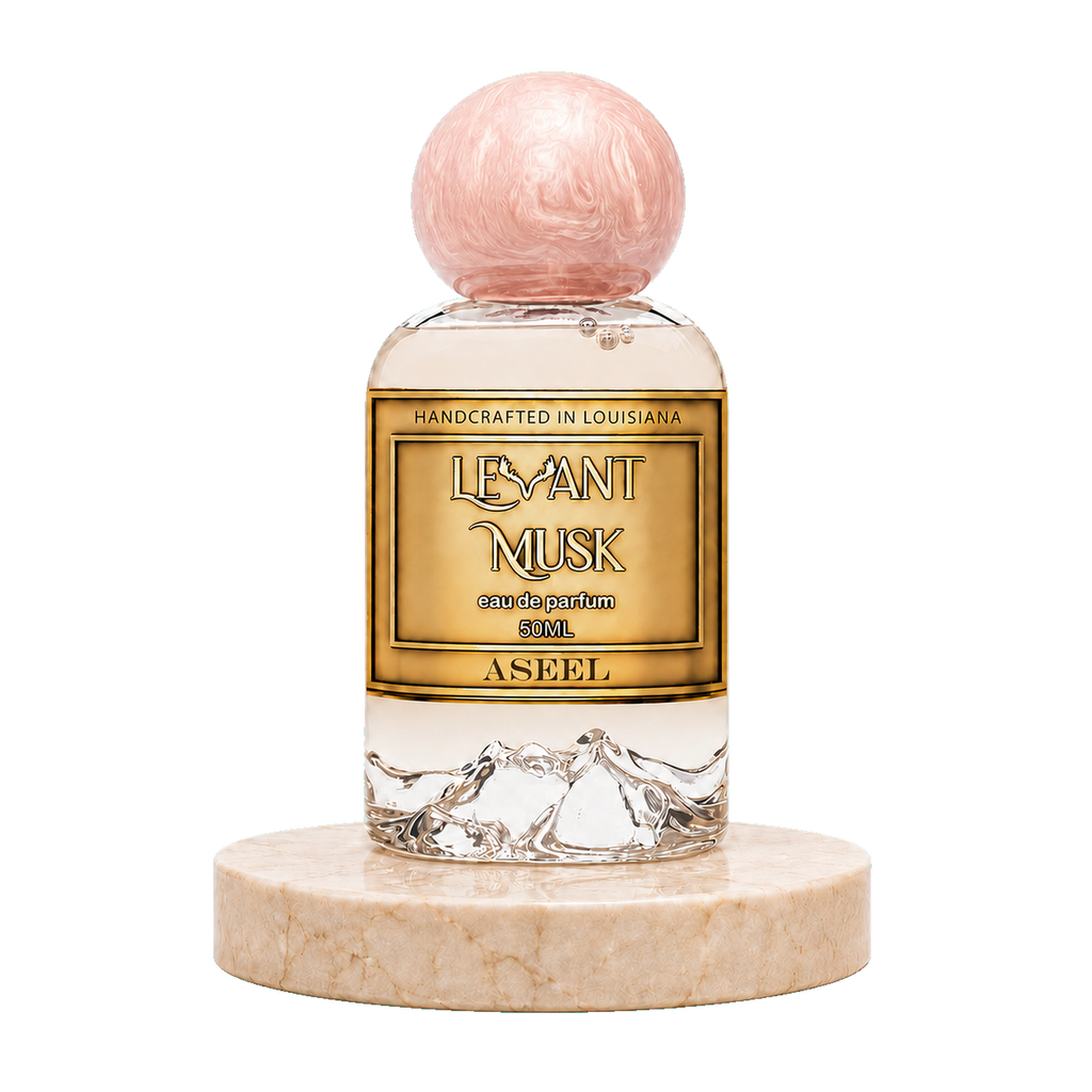 A bottle of ASEEL Levant Musk Eau de Parfum with a gold label and a pink marbled spherical cap, displayed on a round beige marble base against a white background.