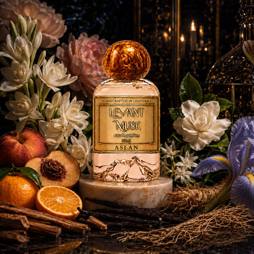 ASLAN by Levant Musk on a marble pedestal, surrounded by white flowers, peach, mandarin, iris, vanilla, sandalwood and vetiver illustrations.