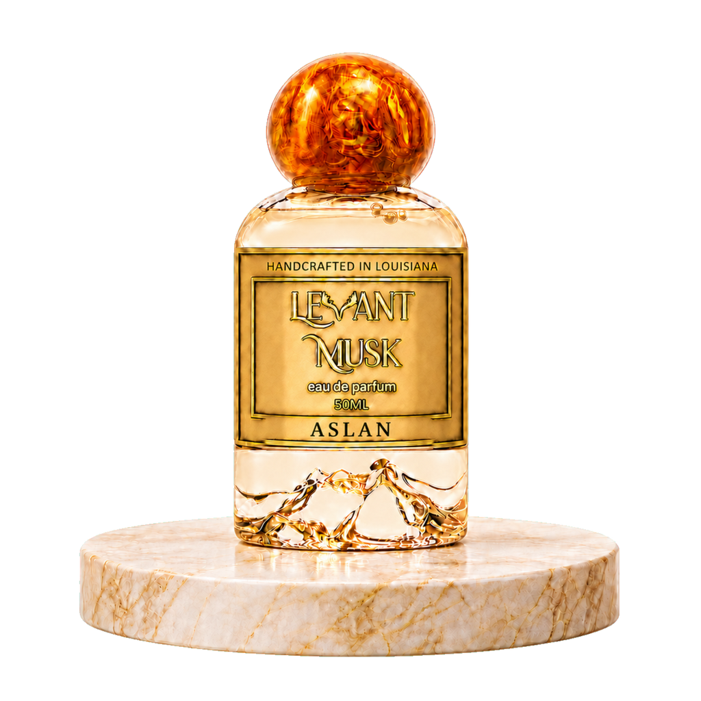 A bottle of ASLAN by Levant Musk, Monroe, LA eau de parfum, featuring a clear glass bottle filled with golden liquid, a gold label, and a textured amber-brown spherical cap, displayed on a round beige marble pedestal against a white background.