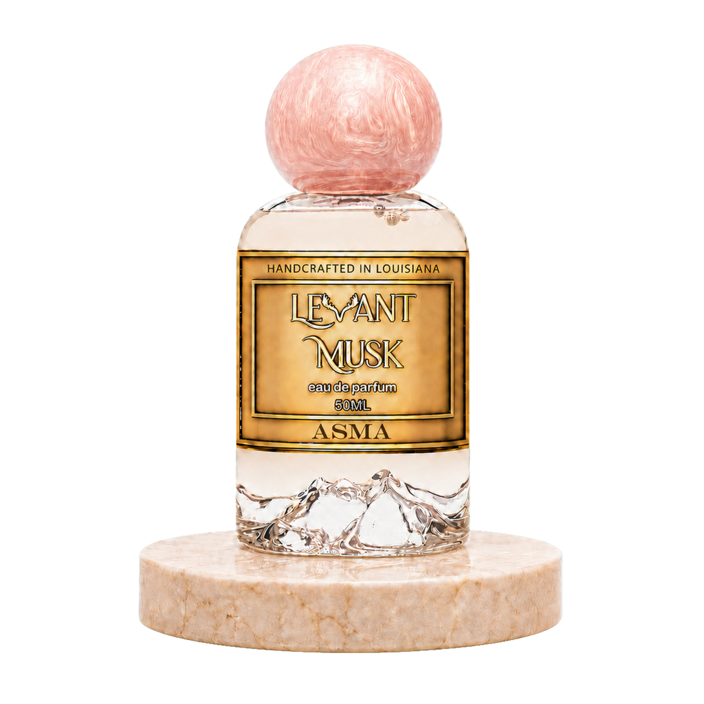 A bottle of ASMA by Levant Musk eau de parfum with a gold label and a pink marbled spherical cap, displayed on a round beige marble base against a white background.