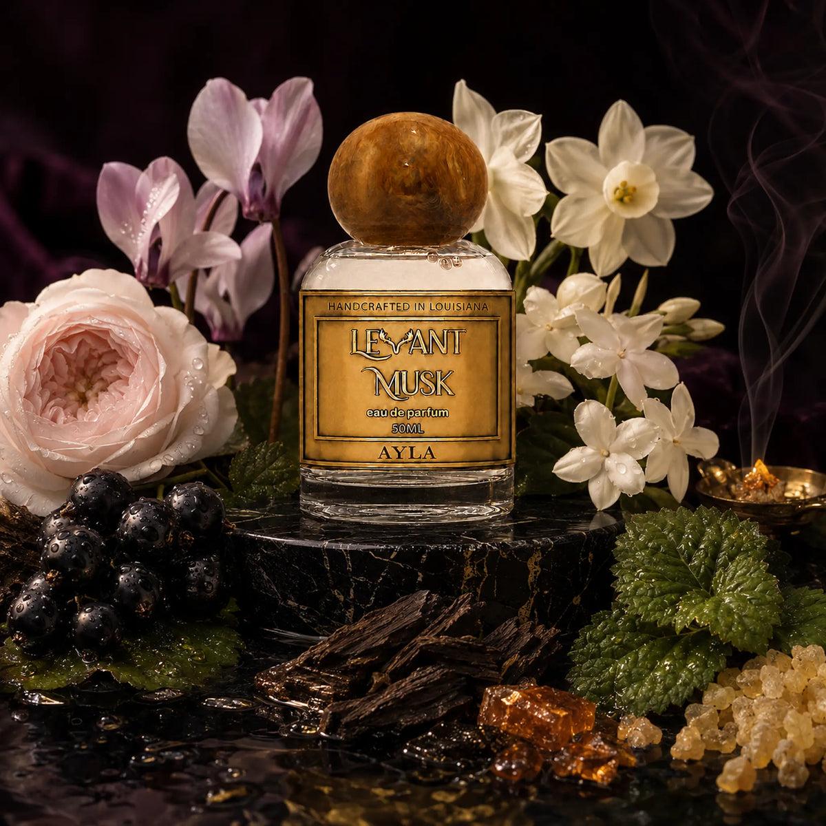 A 50 ml perfume bottle labeled Ayla eau de parfum by Levant Musk, styled on a dark stone pedestal with white and pink flowers, green leaves, dark berries, amber pieces, and a smoky dark background.