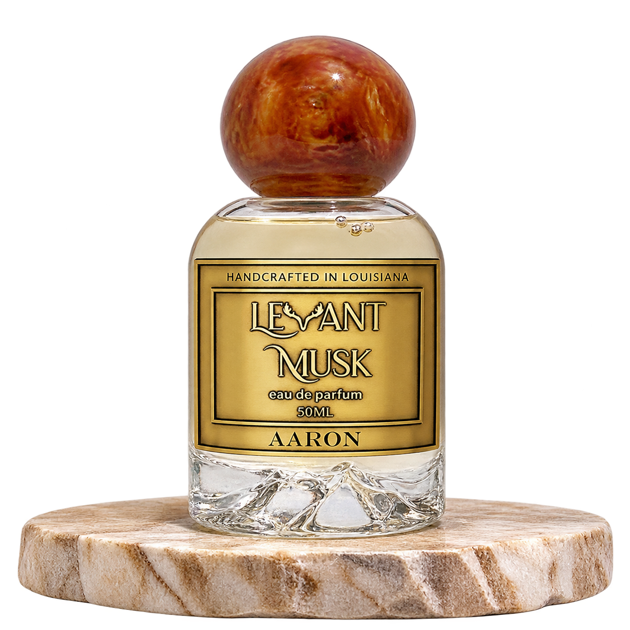 A bottle of Levant Musk Eau de Parfum labeled Aaron, featuring a clear glass bottle with a round amber-brown wooden cap and a gold label, displayed on a round marble coaster against a white background.