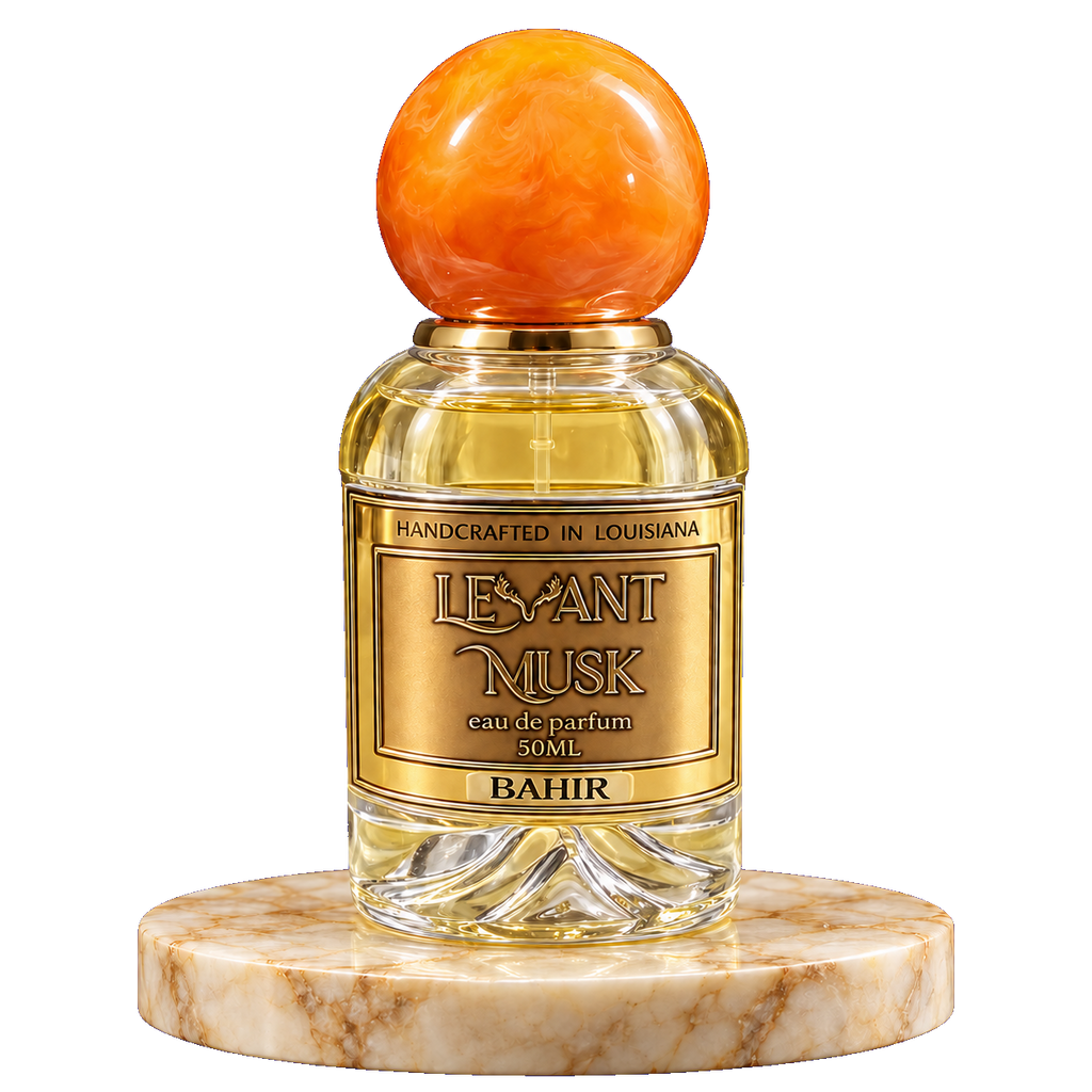 A 50ml bottle of Levant Musk Eau de Parfum named Bahir, featuring a round orange agate stopper and a gold label, displayed on a round white and brown marble pedestal against a white background.