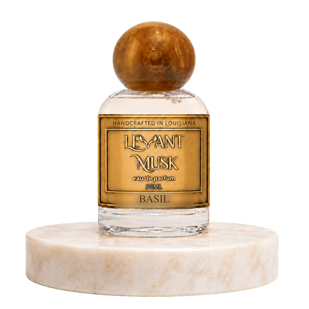 A 50ml bottle of Marwan 'Levant Musk' handcrafted perfume, featuring a clear glass body, amber-colored liquid, a gold label, and a polished amber sphere cap, displayed on a white marble pedestal against a white background.