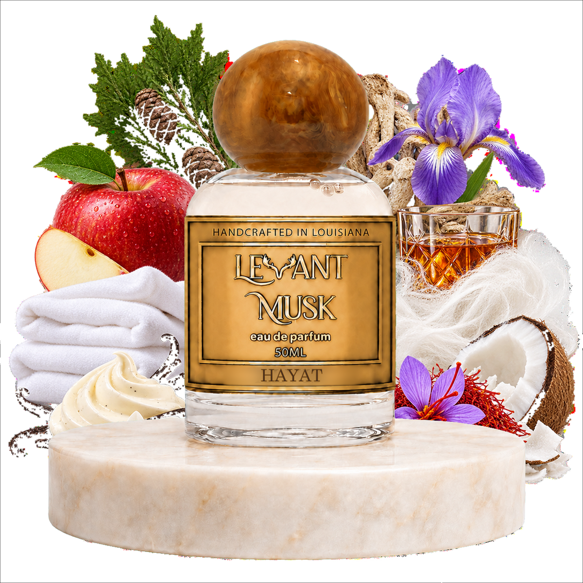 A bottle of Hayat by Levant Musk handcrafted fragrance  in a clear glass bottle with a round amber cap, displayed on a marble pedestal with scent notes including an apple, folded white towels, purple irises, coconut, and a glass of amber liquid.