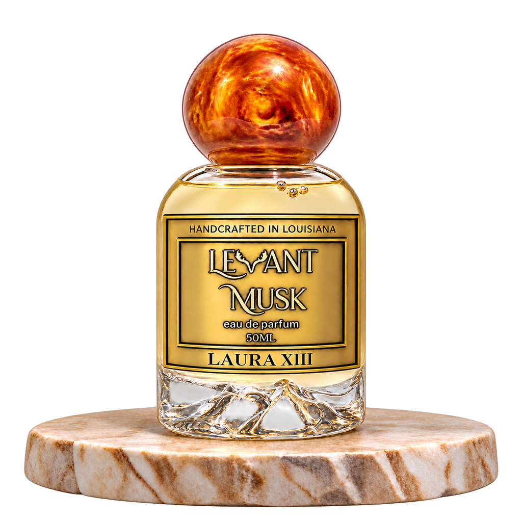 LAURA XIII by Levant Musk, 50 mL eau de parfum with a orange-gold marble cap on a cream marble plinth, transparent background.