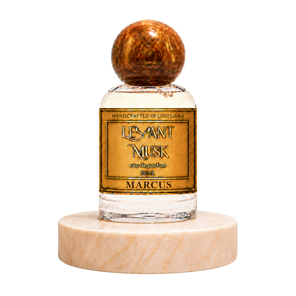 A 50ml bottle of Marcus eau de parfum by Levant Musk, featuring a clear glass bottle with a gold label, topped with a polished brown wooden sphere cap and resting on a round white marble base, set against a plain white background.