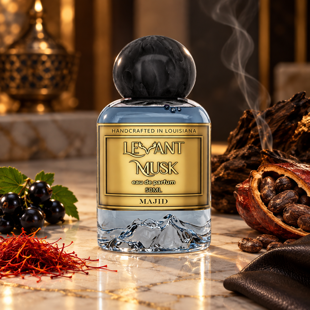 A bottle of Majid Levant Musk Eau de Parfum with a gold label and a black marble cap, styled on a marble surface with rose petals, saffron, pomegranate, and blackberries.