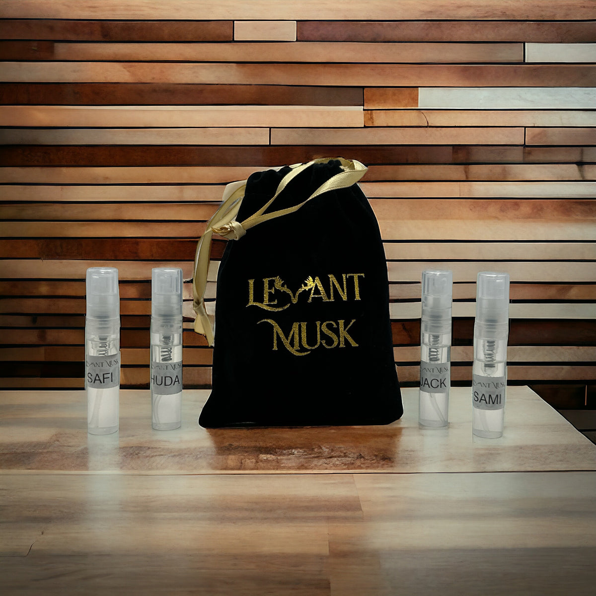 Four Levant Musk sample spray vials beside a black drawstring pouch with gold lettering and ribbon.