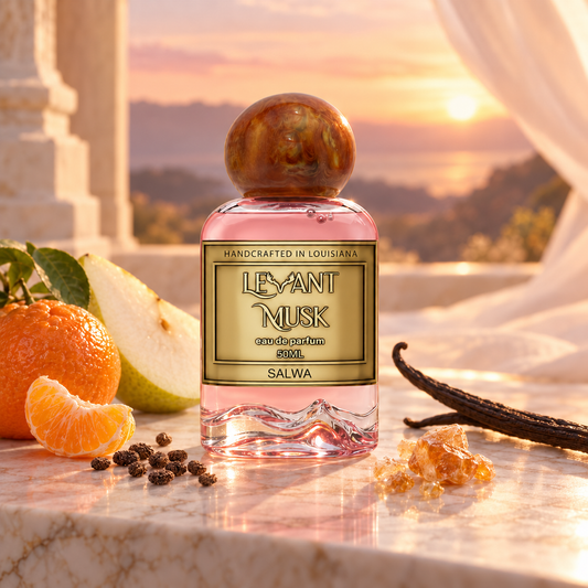 A bottle of Salwa by Levant Musk perfume is displayed on a marble surface with citrus, vanilla bean, and spices, set against a warm sunset background.