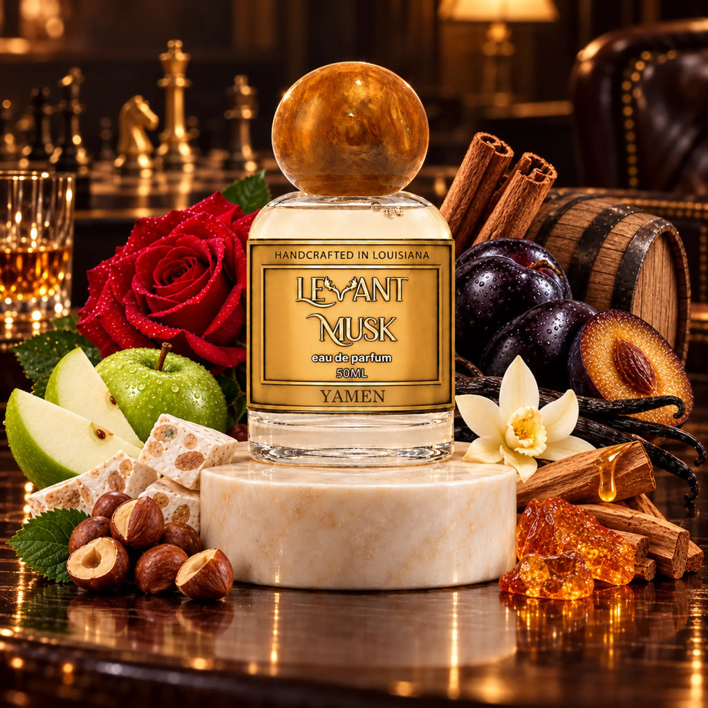 A bottle of Levant Musk Yamen eau de parfum is displayed on a marble pedestal, surrounded by its scent ingredients including a red rose, green apple, honeycomb, hazelnuts, cinnamon sticks, plums, vanilla flower, and amber resin, set against a warm, dark bar background.
